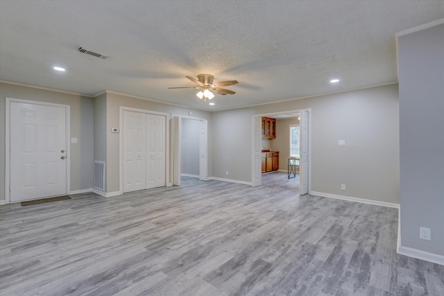 interior space with ceiling fan, a textured ceiling, ornamental molding, and light wood-type flooring