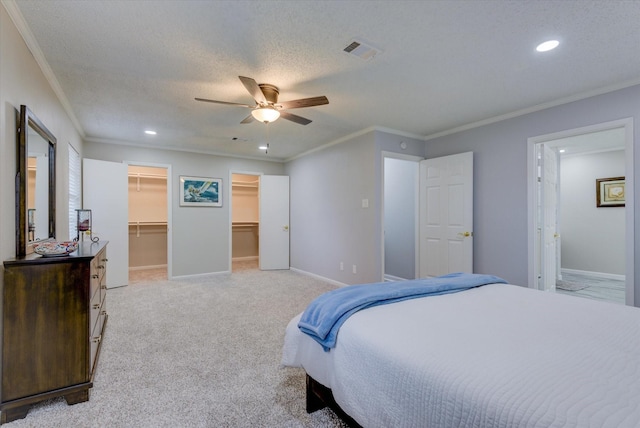 bedroom with a spacious closet, ceiling fan, a closet, a textured ceiling, and ornamental molding