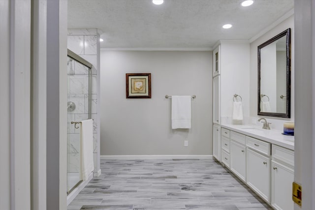 bathroom featuring vanity, crown molding, hardwood / wood-style flooring, a textured ceiling, and a shower with door