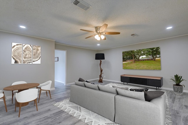 living room featuring a textured ceiling, ceiling fan, ornamental molding, and hardwood / wood-style floors