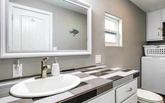 bathroom featuring vanity, washer / dryer, and toilet