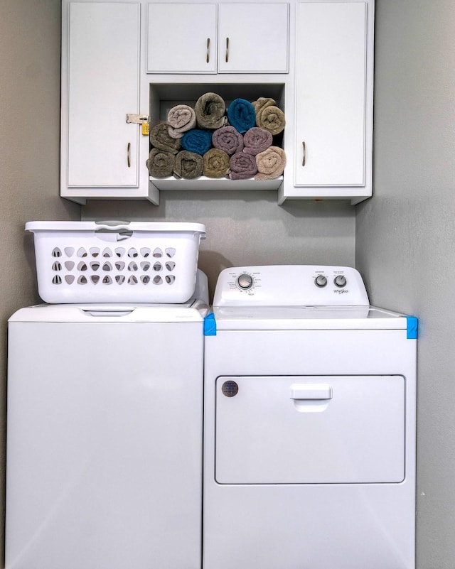 clothes washing area featuring cabinets and independent washer and dryer