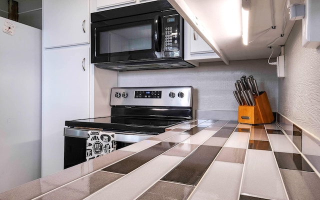 kitchen with white refrigerator, white cabinets, and electric stove