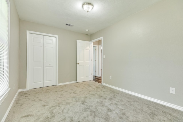 unfurnished bedroom featuring light carpet and a closet