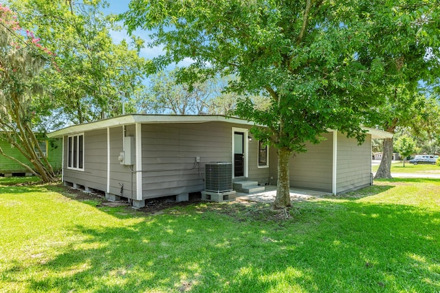 rear view of property featuring central AC, a carport, and a yard