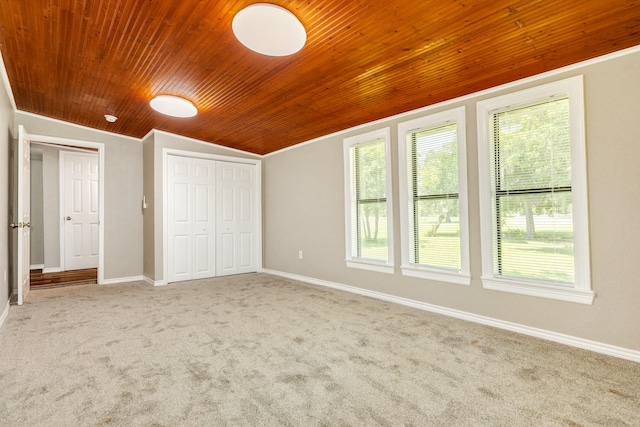 unfurnished bedroom featuring carpet floors, vaulted ceiling, wooden ceiling, and a closet