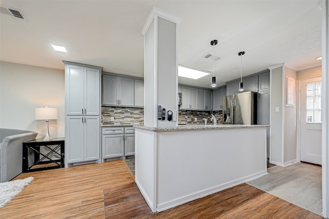 kitchen featuring light hardwood / wood-style floors, tasteful backsplash, gray cabinets, light stone counters, and stainless steel fridge with ice dispenser