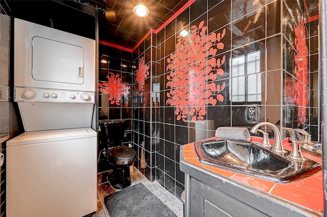 bathroom featuring stacked washer and clothes dryer, tile walls, toilet, and large vanity