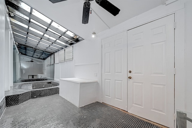 interior space with ceiling fan and tiled tub