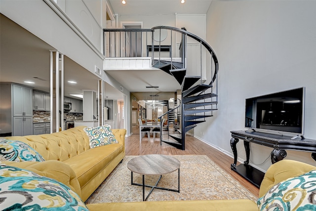 living room with light hardwood / wood-style floors and a high ceiling