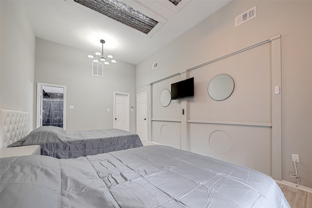 bedroom with a notable chandelier, a towering ceiling, and light hardwood / wood-style floors