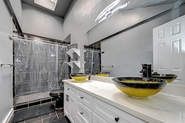 bathroom featuring tile floors, vanity with extensive cabinet space, a shower with curtain, toilet, and dual sinks