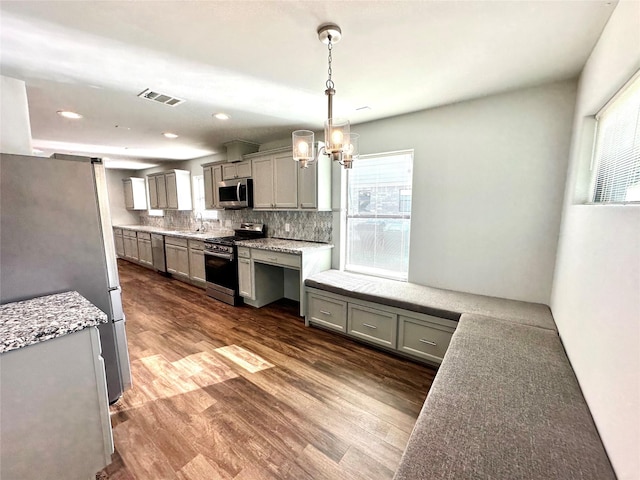 kitchen with dark hardwood / wood-style floors, decorative light fixtures, tasteful backsplash, appliances with stainless steel finishes, and sink