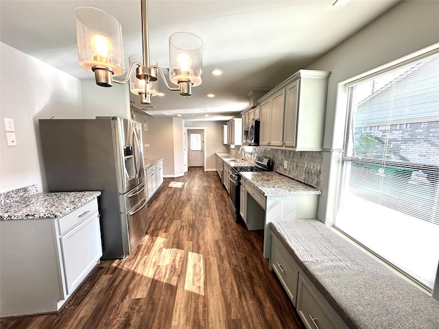 kitchen featuring decorative backsplash, dark hardwood / wood-style flooring, a chandelier, pendant lighting, and appliances with stainless steel finishes