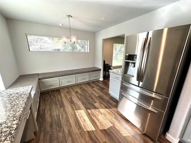 kitchen with hanging light fixtures, light stone countertops, a notable chandelier, dark hardwood / wood-style flooring, and stainless steel refrigerator with ice dispenser