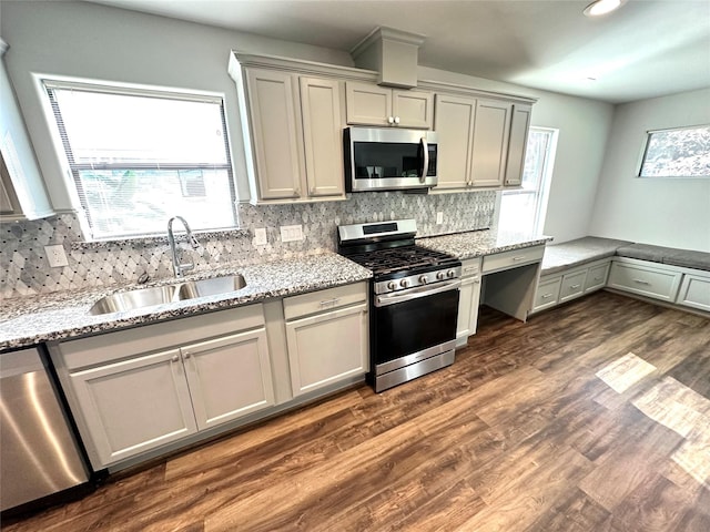 kitchen with light stone countertops, dark wood-type flooring, appliances with stainless steel finishes, and sink