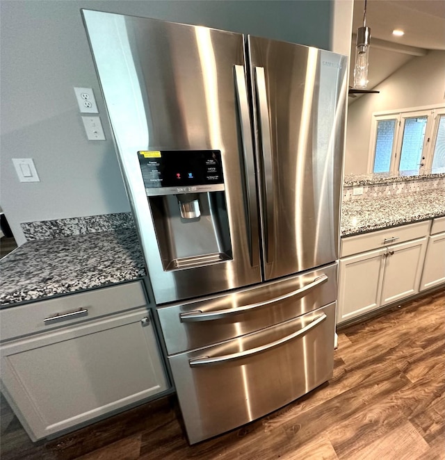 kitchen with white cabinetry, dark wood-type flooring, stone counters, and stainless steel fridge