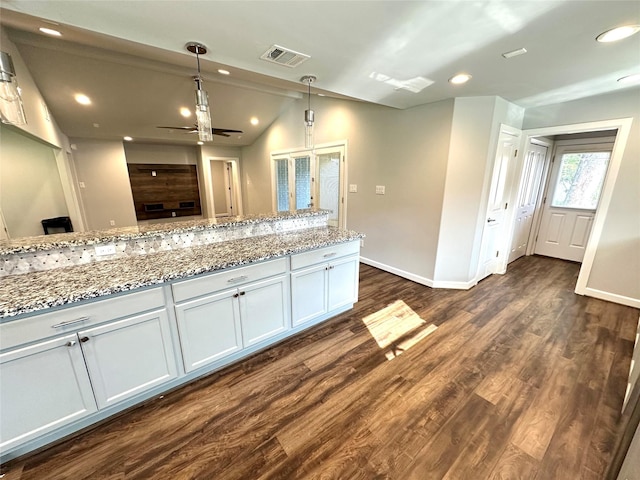 kitchen with light stone counters, dark wood-type flooring, decorative light fixtures, white cabinetry, and ceiling fan