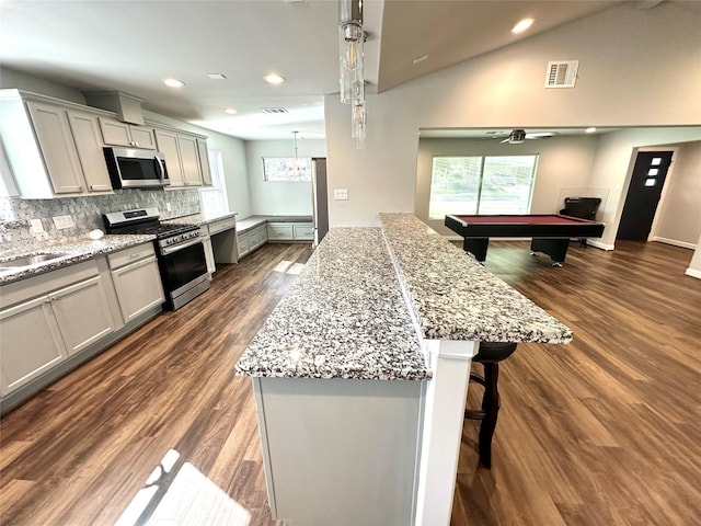 kitchen with pool table, stainless steel appliances, light stone counters, and a kitchen island