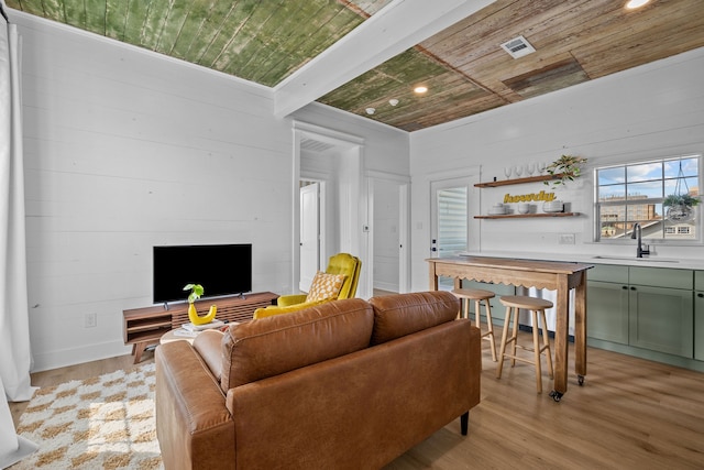 living room featuring wooden ceiling, sink, beam ceiling, and light hardwood / wood-style floors