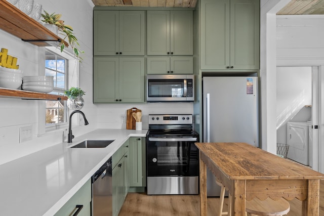 kitchen with sink, light hardwood / wood-style floors, green cabinets, and appliances with stainless steel finishes