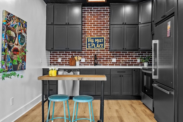 kitchen with gray cabinetry, appliances with stainless steel finishes, sink, and light hardwood / wood-style floors