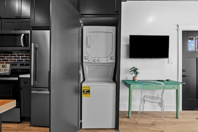 laundry room featuring stacked washer / drying machine and light wood-type flooring