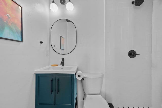 bathroom featuring a tile shower, vanity, and toilet