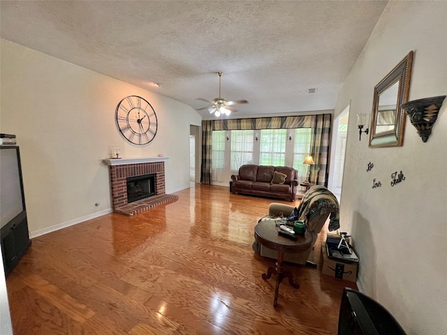 living room featuring lofted ceiling, hardwood / wood-style flooring, ceiling fan, a fireplace, and a textured ceiling