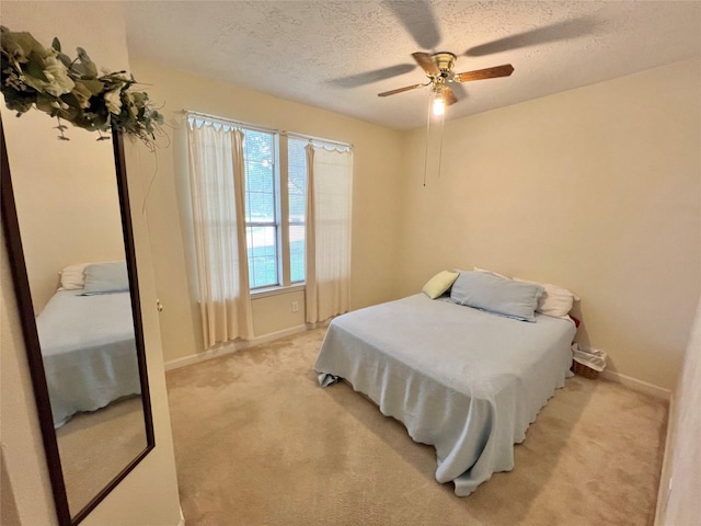 carpeted bedroom featuring ceiling fan and a textured ceiling