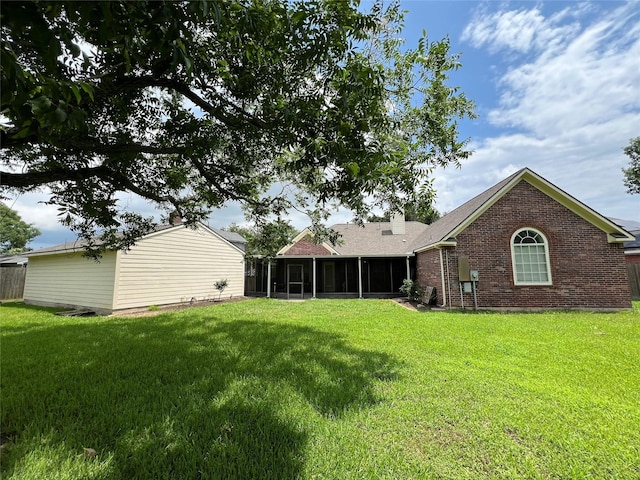 back of house with a sunroom and a lawn