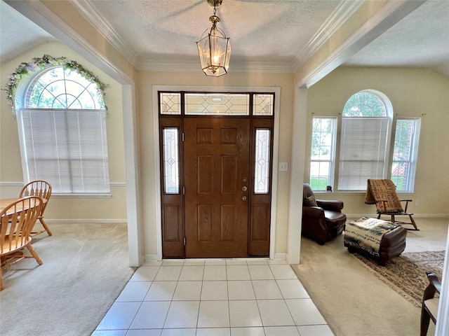 tiled foyer entrance with a chandelier, crown molding, a textured ceiling, and vaulted ceiling