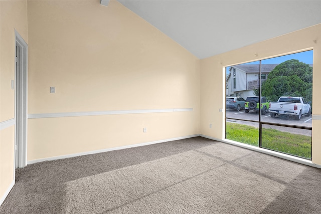 carpeted spare room featuring high vaulted ceiling