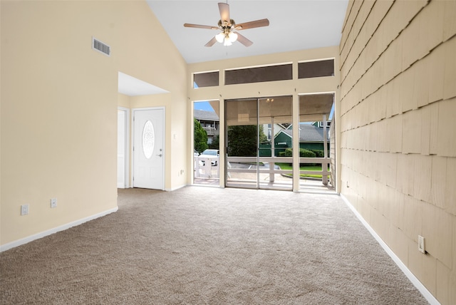 empty room with high vaulted ceiling, ceiling fan, and carpet flooring