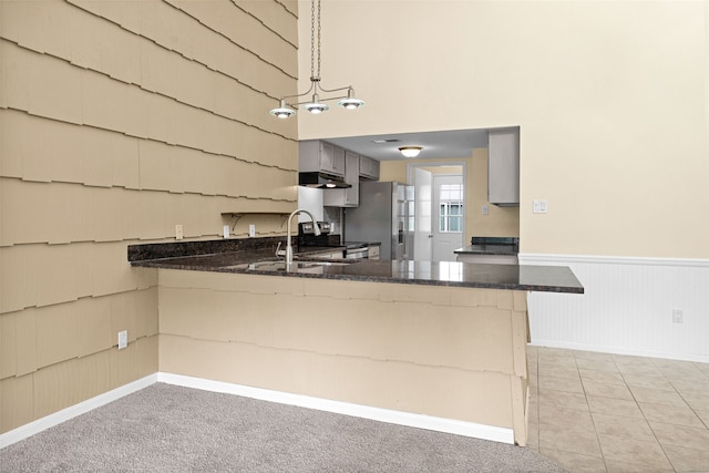 kitchen featuring light carpet, decorative light fixtures, appliances with stainless steel finishes, and kitchen peninsula