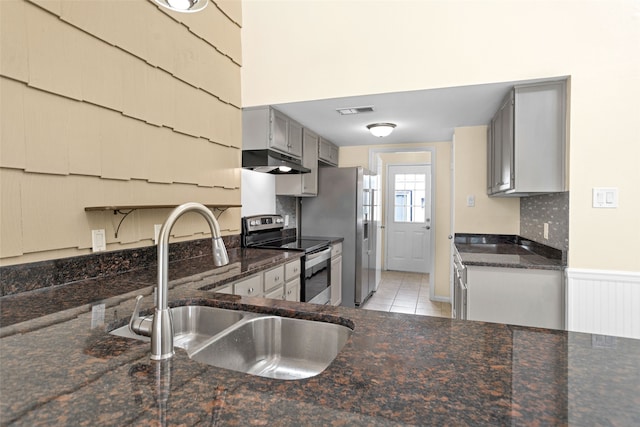 kitchen featuring dark stone counters, stainless steel appliances, light tile floors, gray cabinetry, and sink