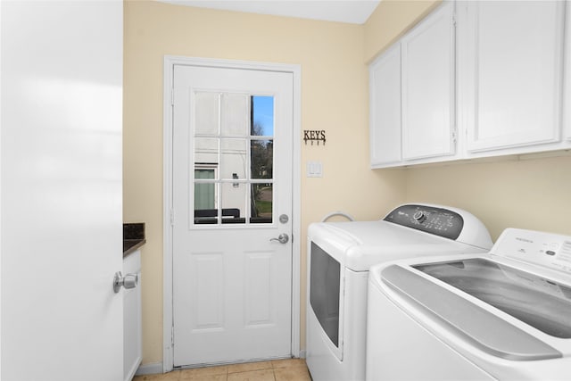 washroom featuring washer and dryer, cabinets, and light tile floors