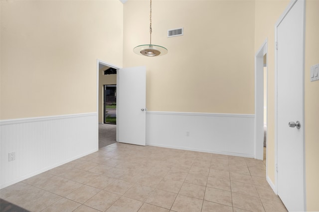 tiled spare room featuring a towering ceiling