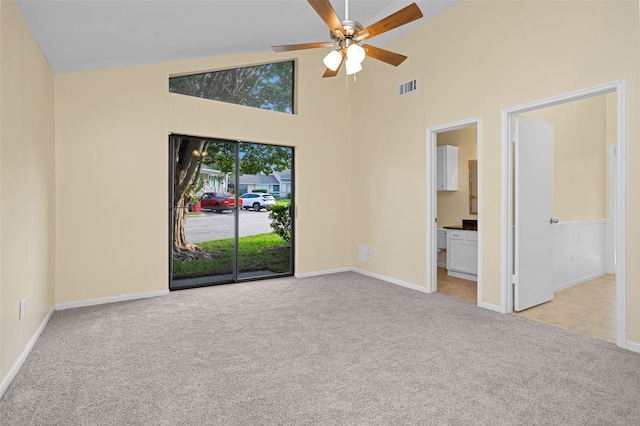 carpeted spare room featuring high vaulted ceiling and ceiling fan