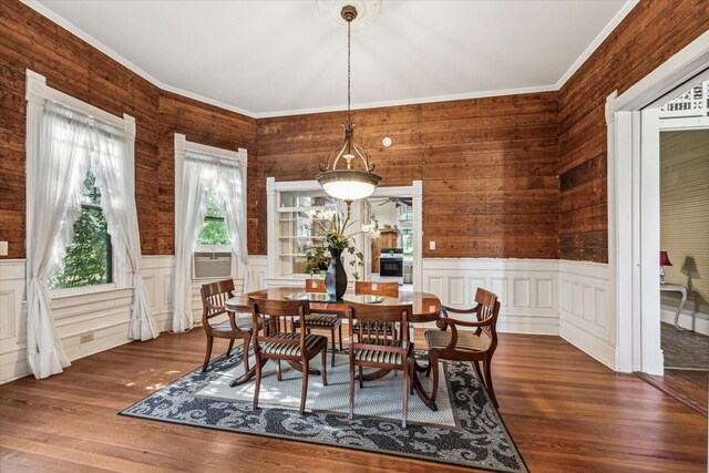 dining area featuring wooden walls, crown molding, and dark wood-type flooring