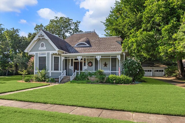 view of front of home featuring a porch, a garage, and a front lawn