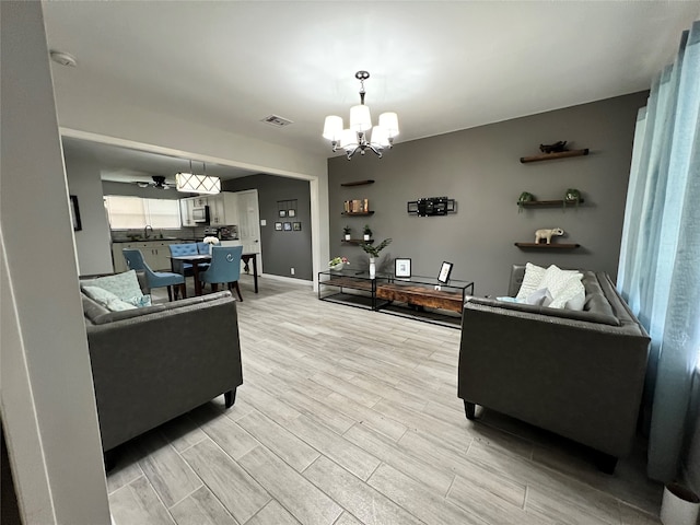 living room with sink, a chandelier, and light hardwood / wood-style floors