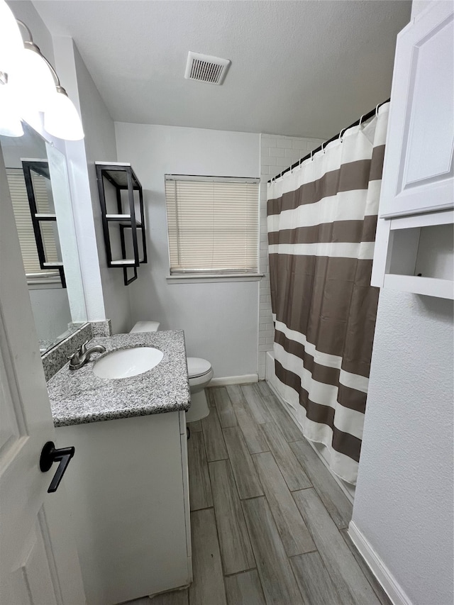 bathroom with toilet, hardwood / wood-style floors, curtained shower, vanity, and a textured ceiling