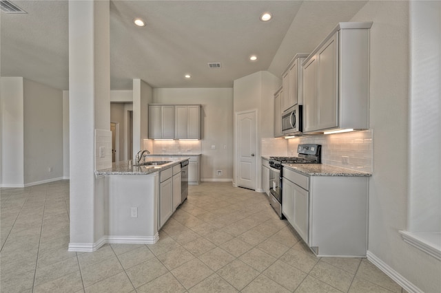 kitchen featuring backsplash, stainless steel appliances, light stone counters, and sink