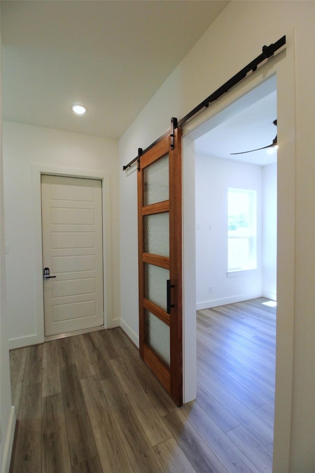 corridor with a barn door and hardwood / wood-style flooring