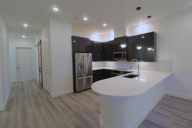 kitchen with decorative light fixtures, stainless steel appliances, decorative backsplash, sink, and kitchen peninsula