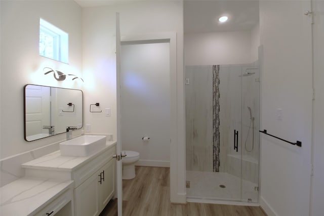 bathroom featuring hardwood / wood-style flooring, toilet, walk in shower, and vanity