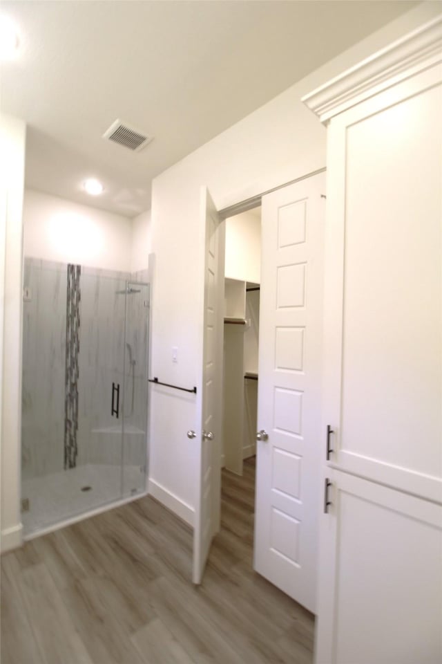 bathroom with hardwood / wood-style flooring and an enclosed shower