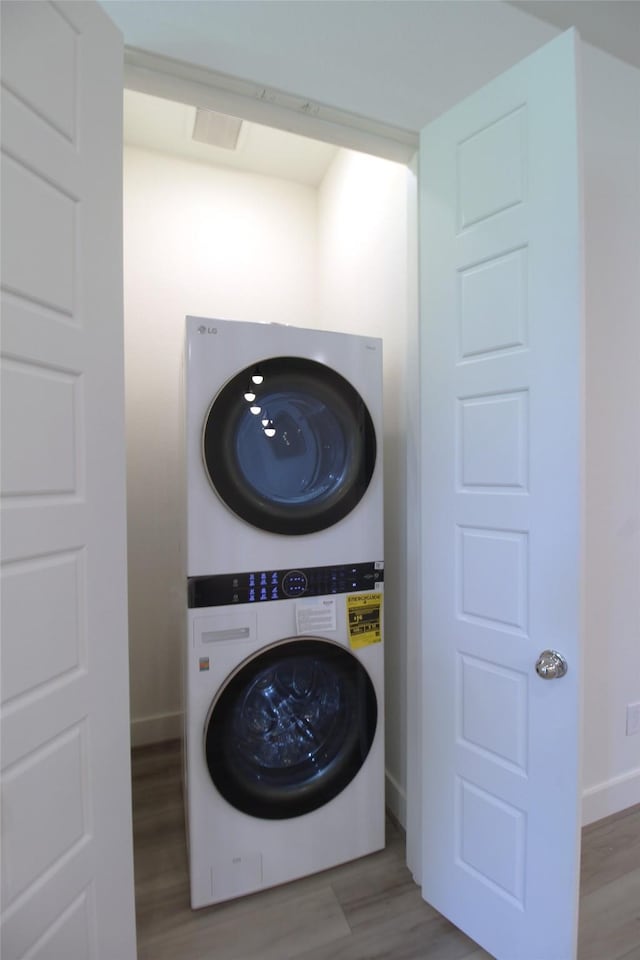 laundry area featuring light wood-type flooring and stacked washer and clothes dryer