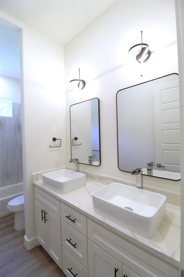 full bathroom featuring hardwood / wood-style flooring, shower / bathing tub combination, toilet, and vanity